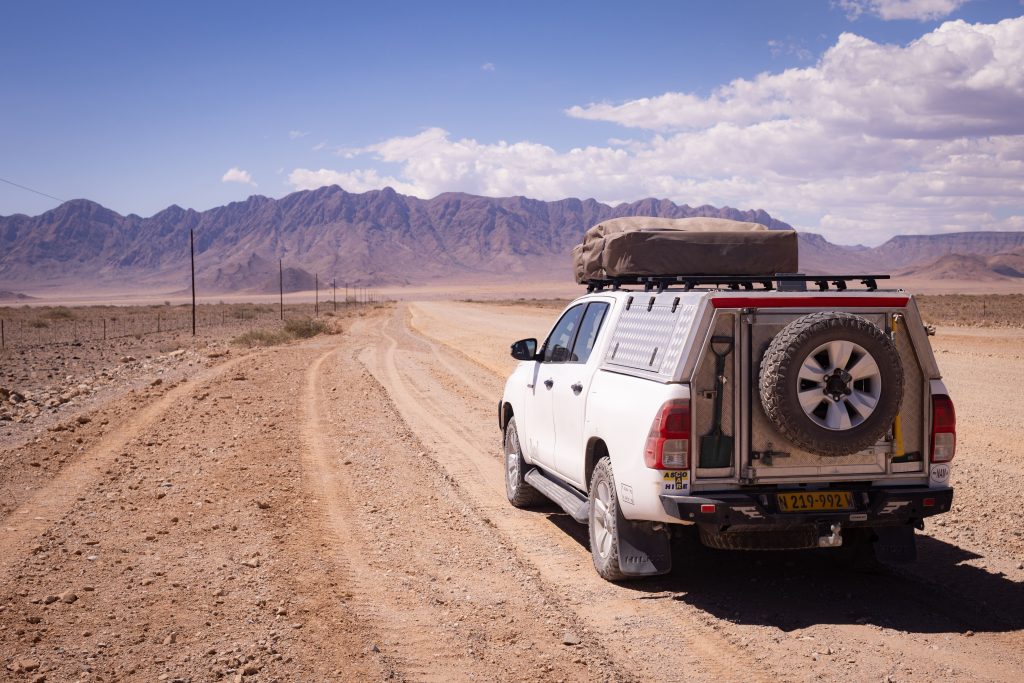 Toyota Hilux auf Schotterpiste in Namibia mit Bergen im Hintergrund