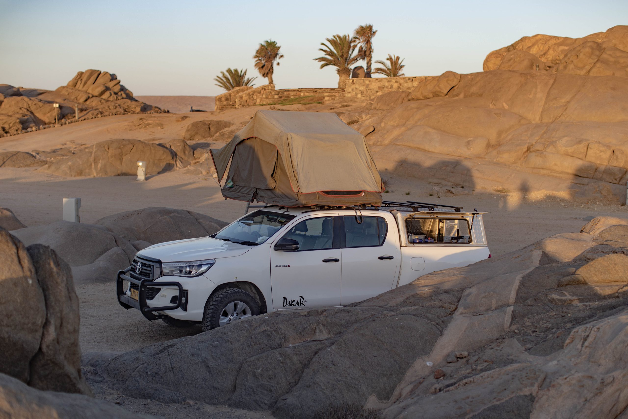 Pickup mit Dachzelt zwischen Felsen auf dem Shark Island Camp (Lüderitz)