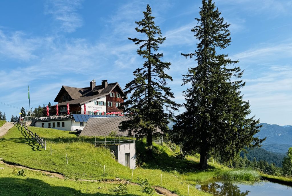 Gablonzer Hütte in den Alpen, im Vordergrund Tannen und ein See
