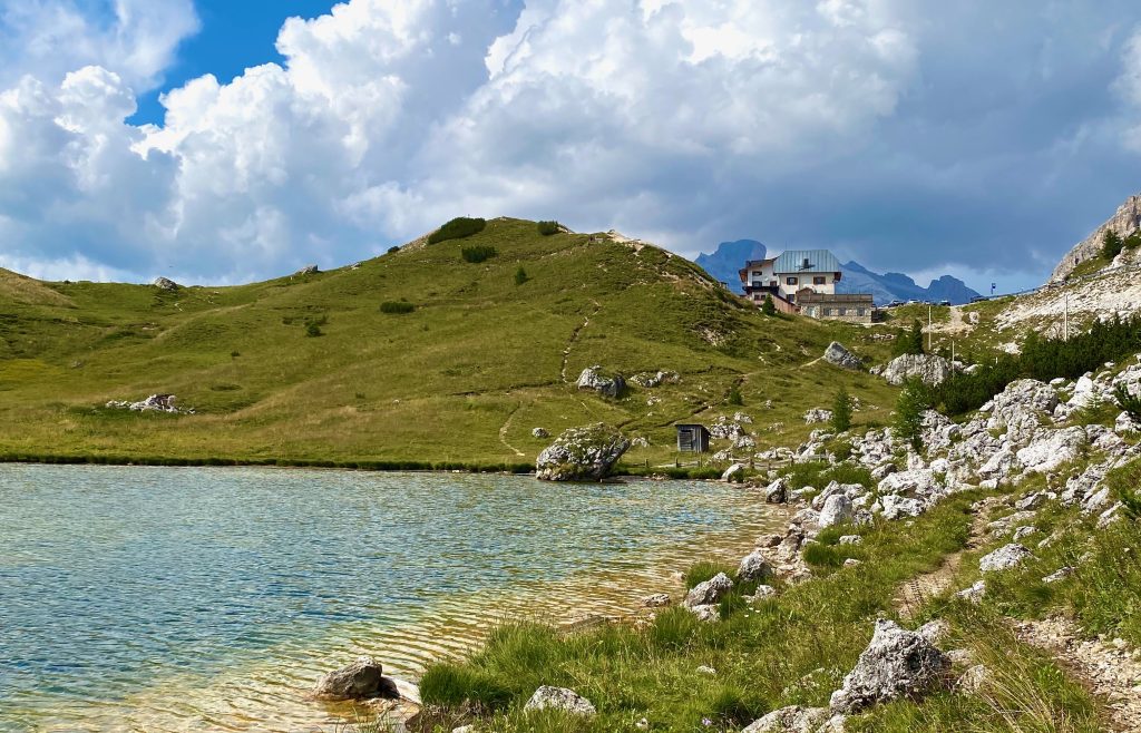 Valparola Hütte im Hintergrund, an einem kleinen See gelegen, der sich im Vordergrund befindet.