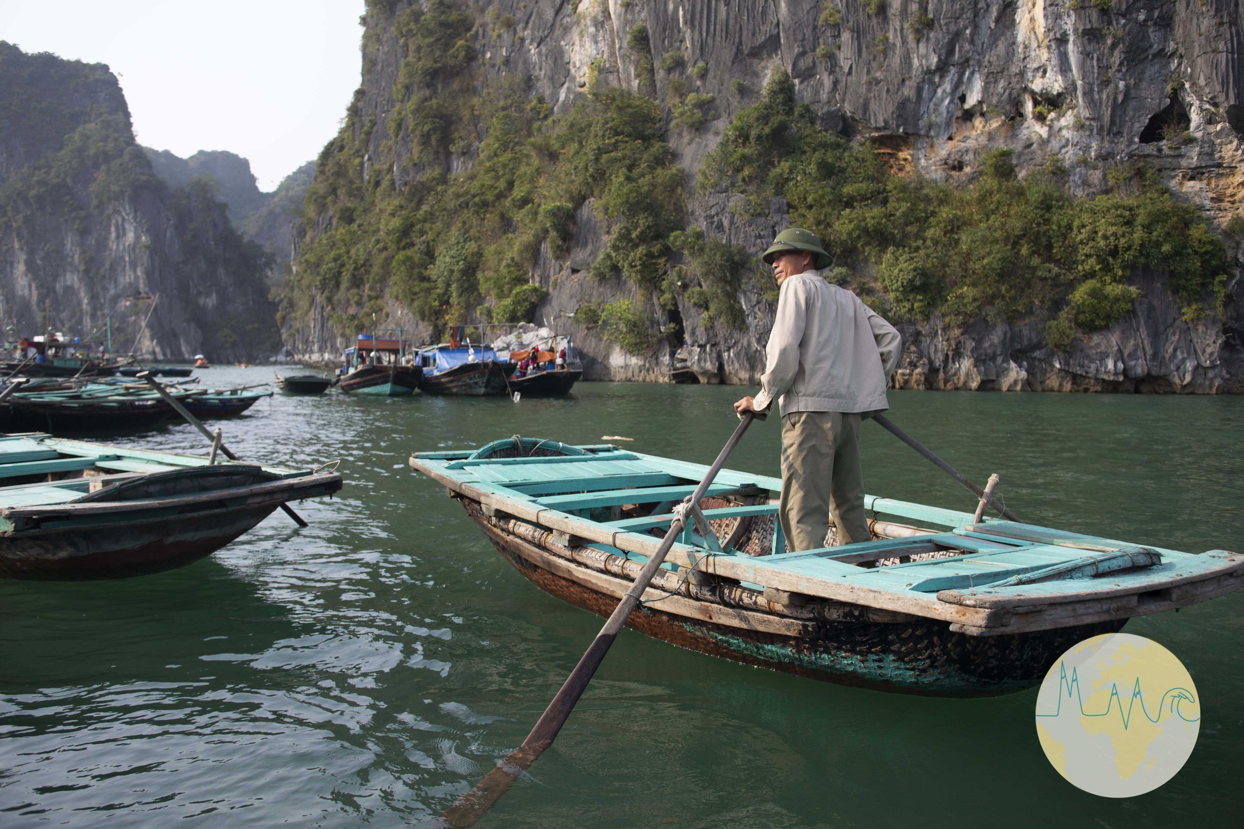 Ha Long Bay - Fischer auf einem Fischerboot stehend und rudernd