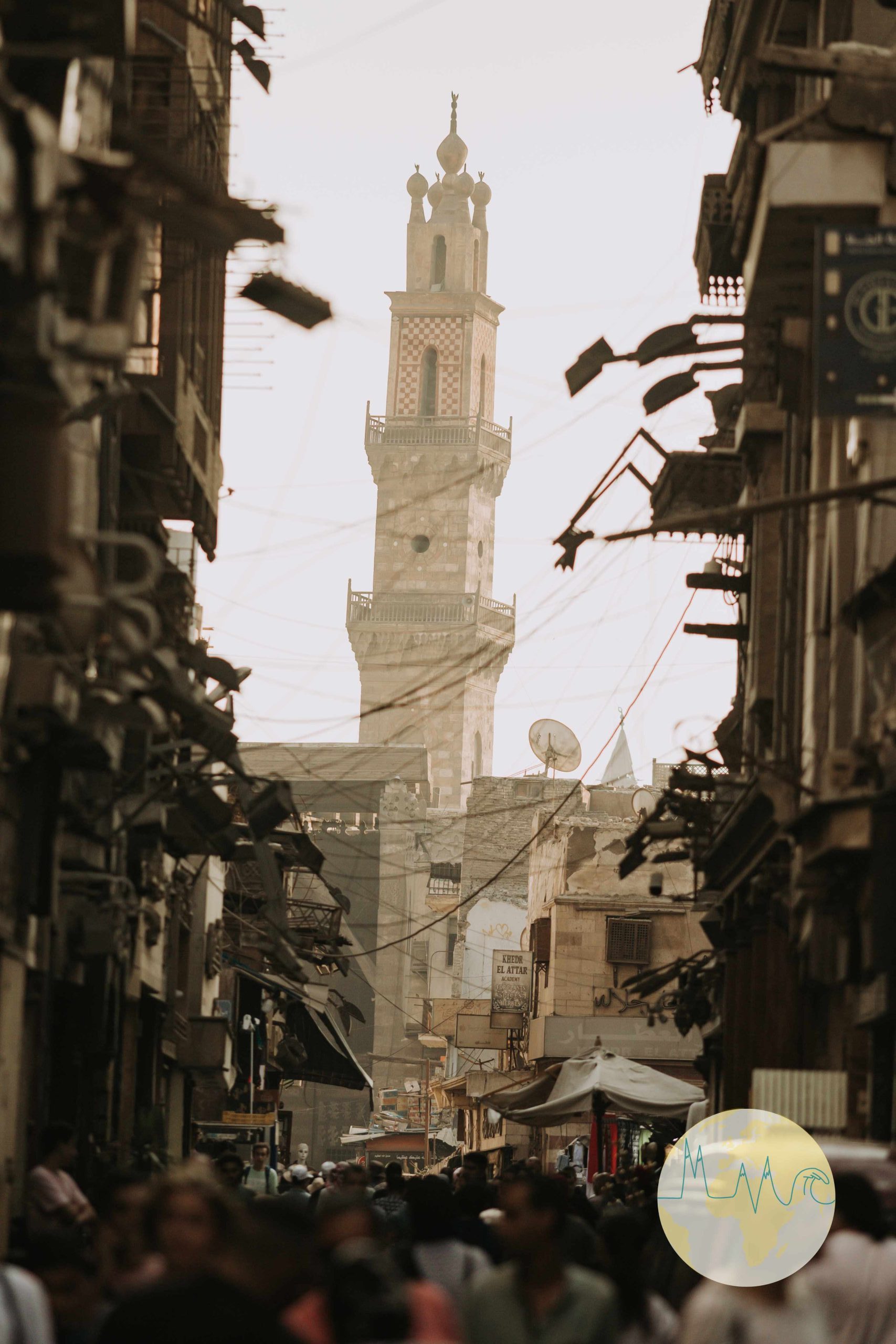 Enge Gasse in Kairo, links und rechts Geschäfte, Blick auf den Turm einer Moschee