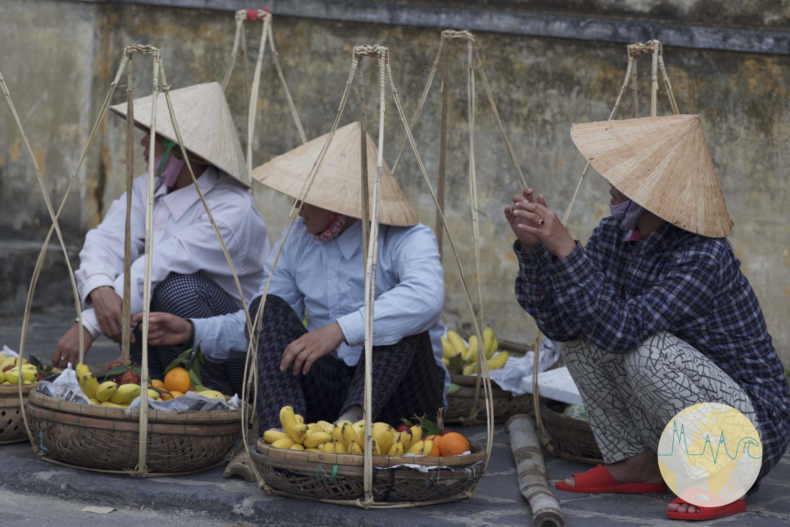 Drei Frauen mit spitzen Hüten am Straßenrand sitzend in Hội An - Vietnam