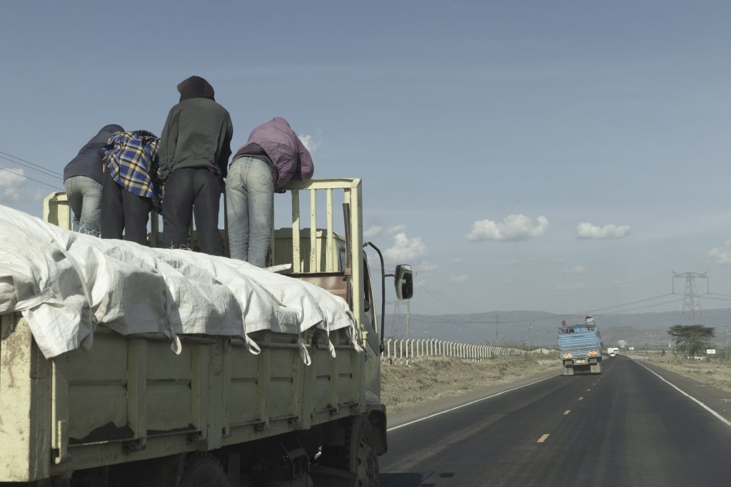 LKW in Kenia mit drei Menschen darauf stehend
