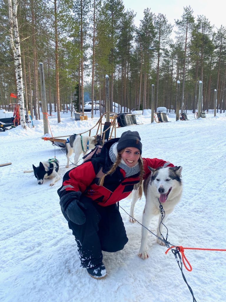 Marianne mit einem Husky bei Rovaniemi vor einem Hundeschlitten in Finnisch-Lappland