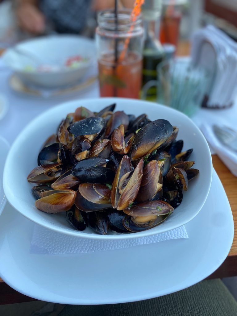 Teller voller Muscheln in einem Restaurant in Sosopol, im Hintergrund ein Cocktail