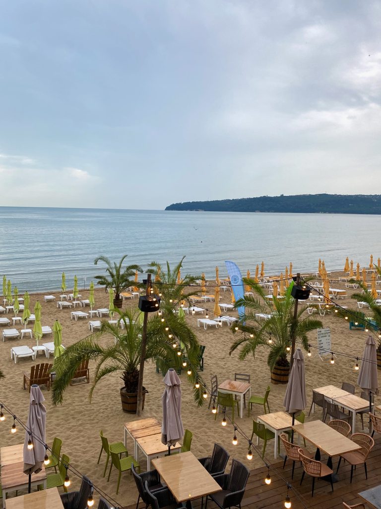 Blick auf den Strand mit Strandbar, Palmen und Liegen in Varna an der Schwarzmeerküste in Bulgarien