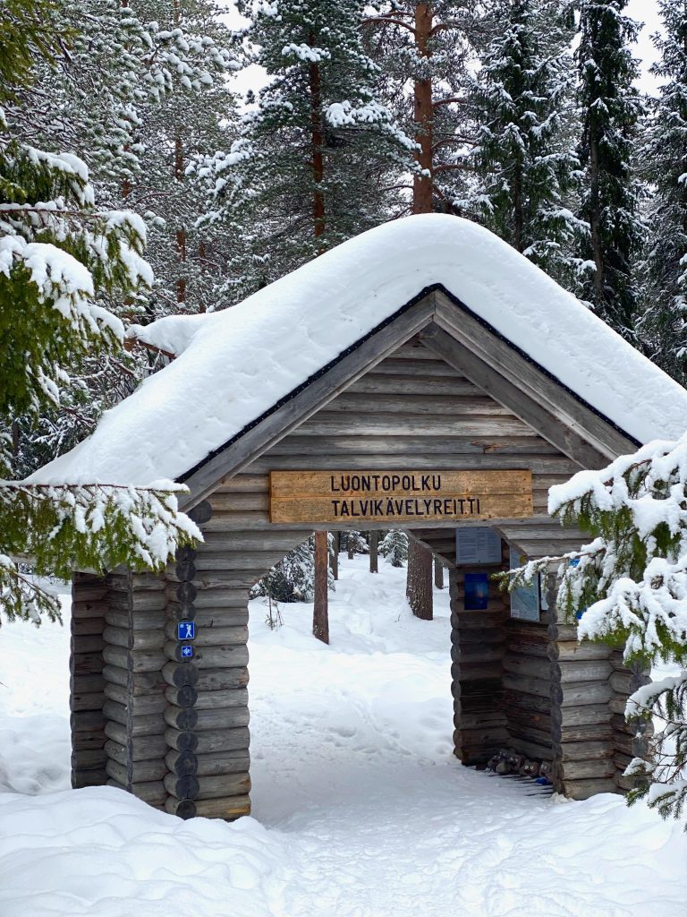 Verschneites Holztor als Eingang zum Winterwanderweg bei Rovaniemi in Finnisch-Lappland