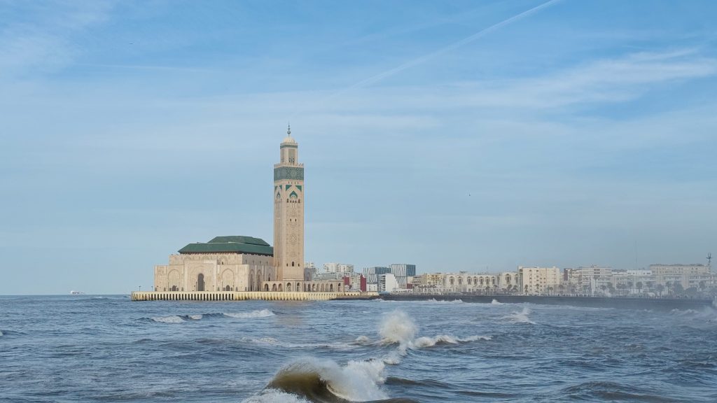 Blick auf die Hassan-II.-Moschee in Casablanca, im Vordergrund die Wellen des Atlantik in Marokko