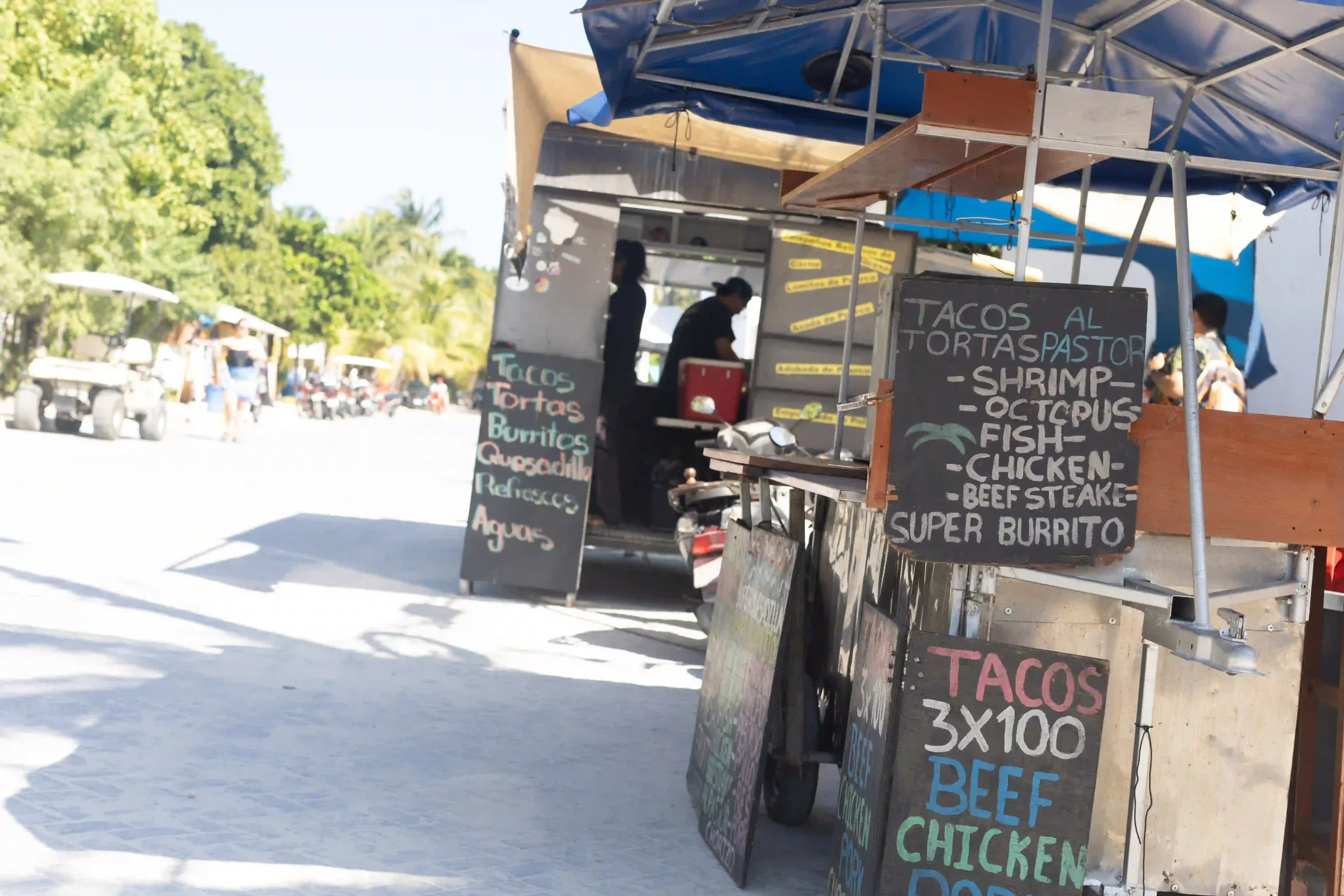 Streetfood-Strände am Straßenrand von Mexiko, davor bunt beschriebene Tafeln