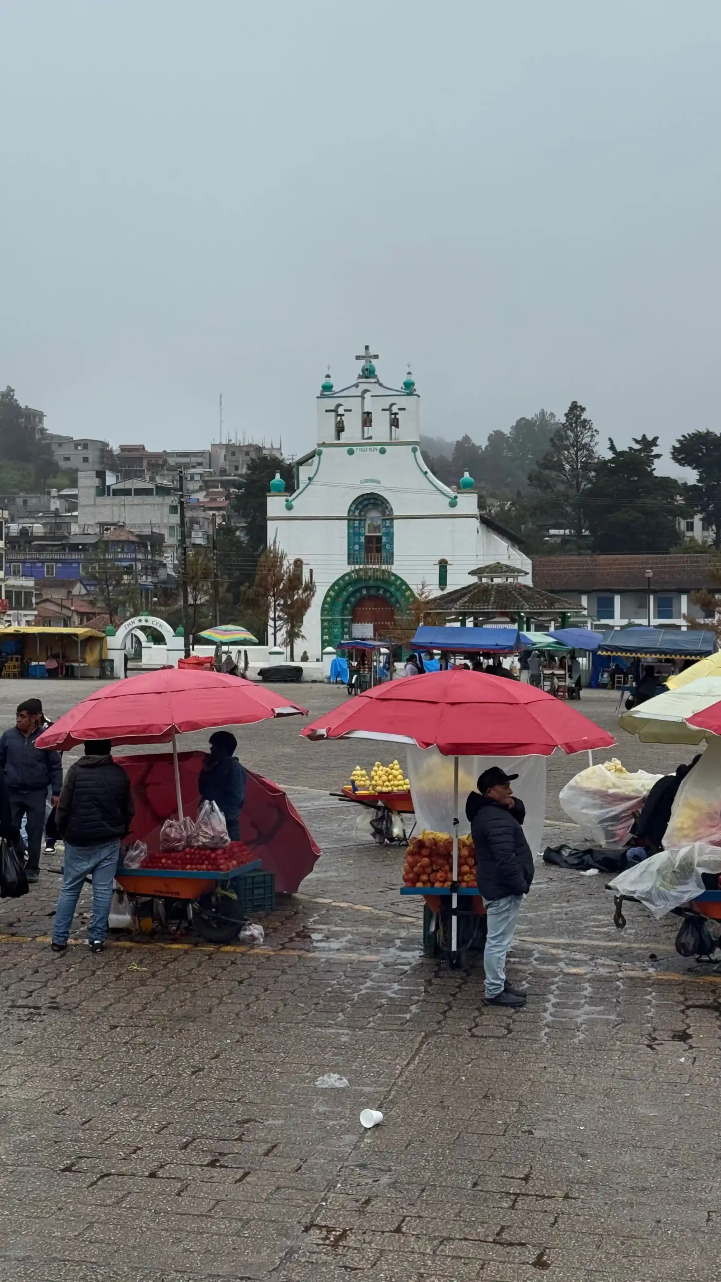 Marktplatz und Kirche und San Juan Chamula bei Regen, im Vordergrund aufgespannte Schirme mit darunter stehenden Menschen